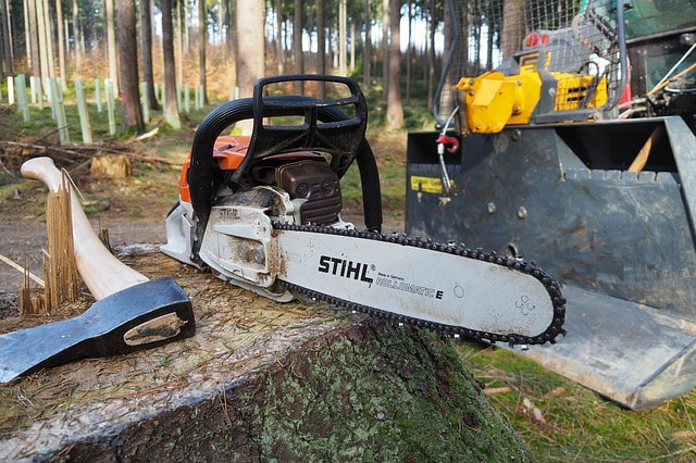 A chainsaw and an ax on a log